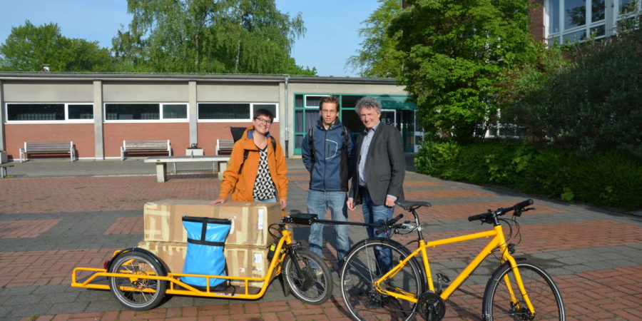 Laura Hebling übergibt für Vamos e.V. die Ausstellung an Schulleiter Christian Schrand und den Schüler Luca Thomas.