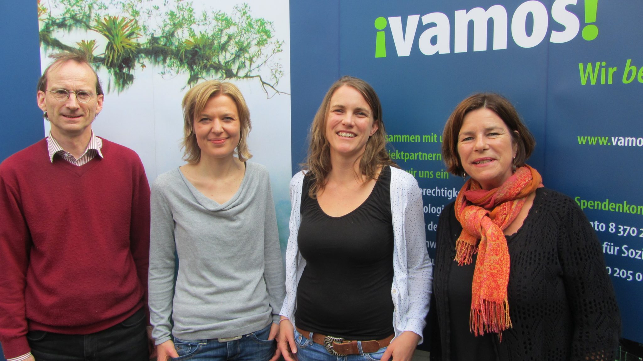 Foto vom Vamos Vorstand, vier Personen vor einem Werbebanner von Vamos