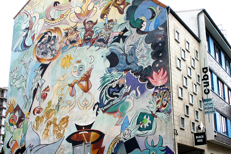 Man sieht ein Haus, das cuba begegnungszentrum, die ganze Fassade ist mit einem bunten Wandbild bemalt.