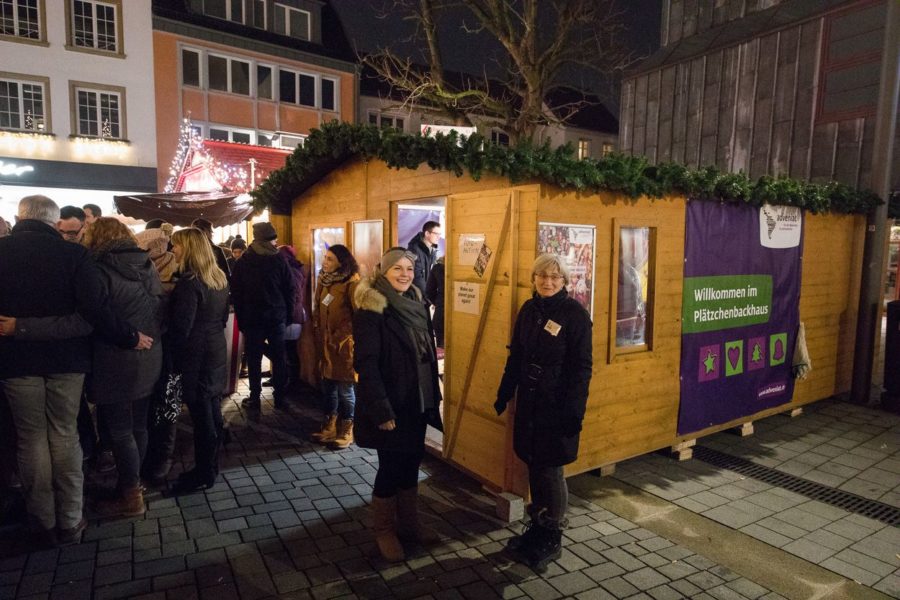 Ein Foto mit einem Weihnachnachts Stand aus Holz von adveniat (für die Menschen in Lateinamerika) und Menschen die davor stehen