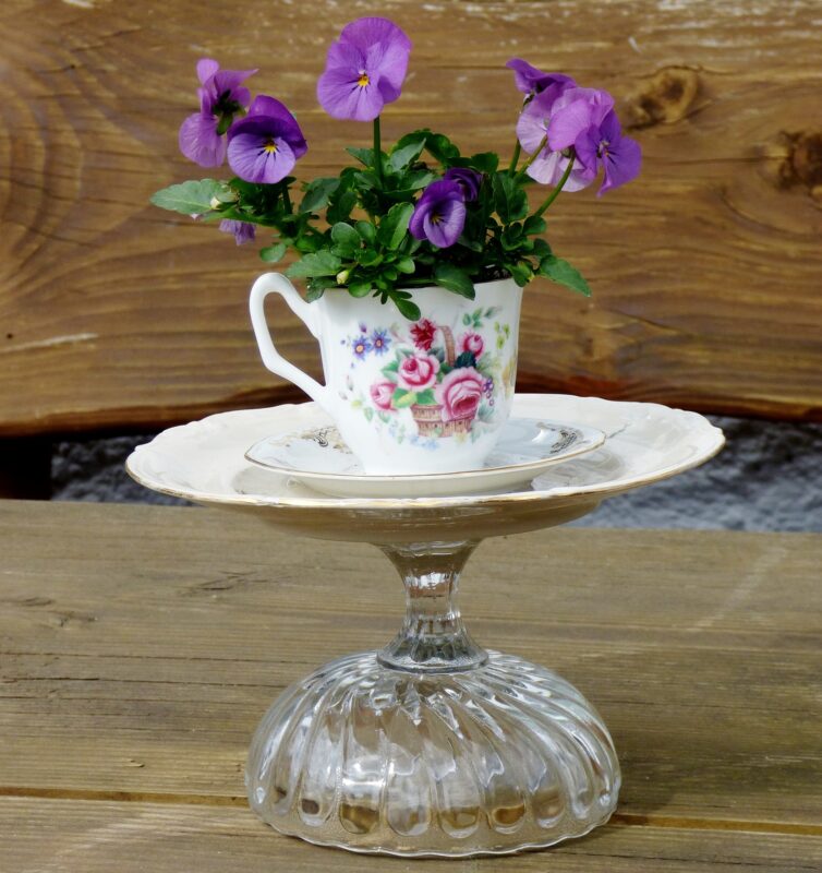 Ein Glas auf dem ein Teller steht mit einer Tasse obendrauf in der eine Blume steht