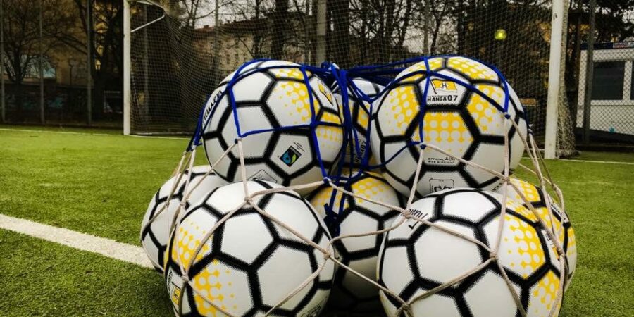 Fußballbälle in einem Netz vor einem Fußballtor