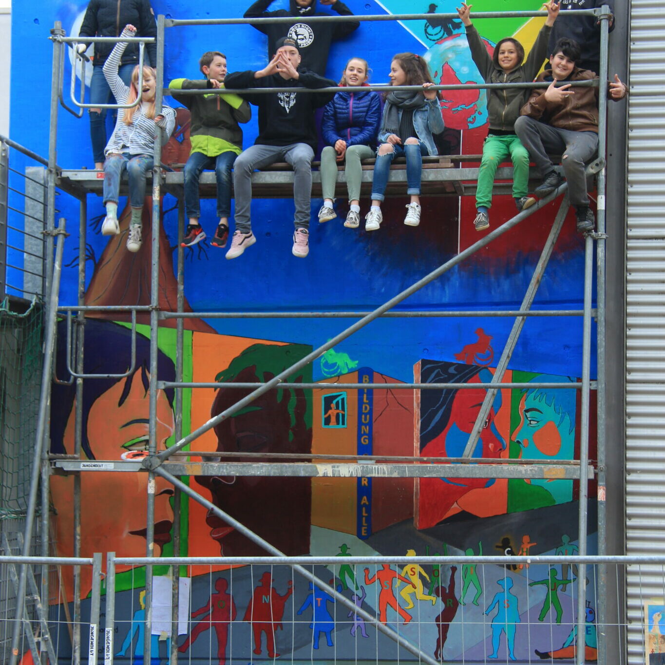 Auf dem Bild von Jorge Hidalgo sieht man ein gemeinsames Gruppenfoto vor dem Wandbild in der Montessorischule.