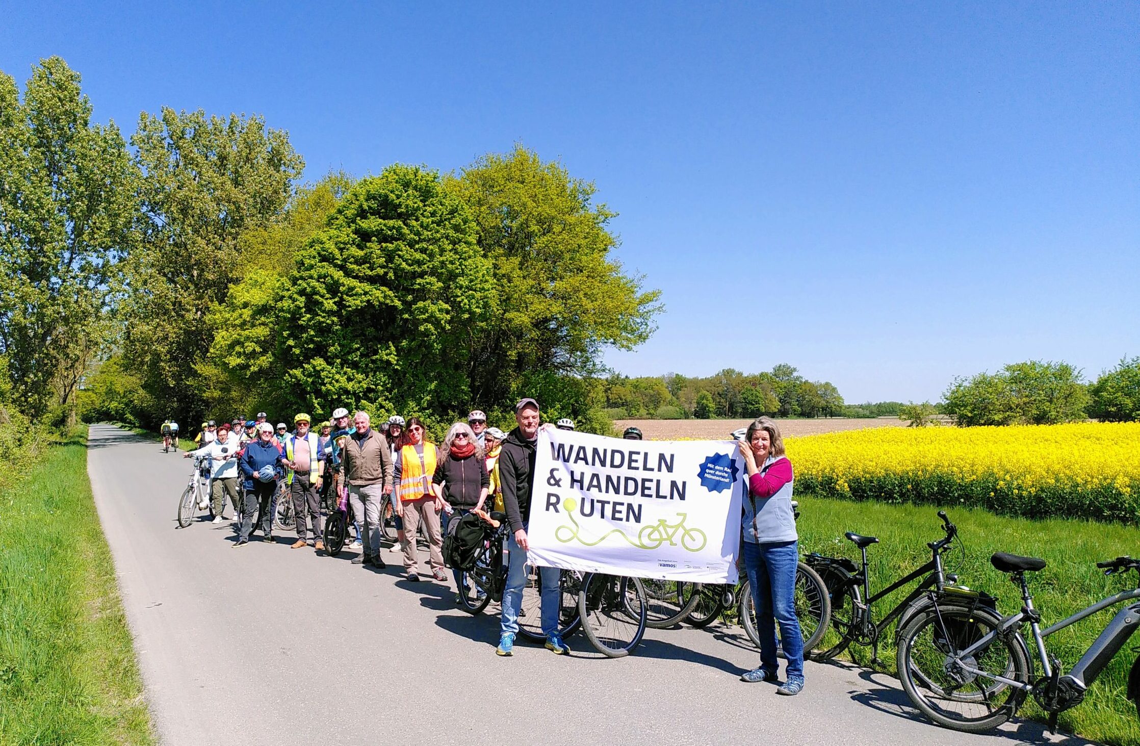 Gruppe vor Rapsfeld mit Banner in Händen